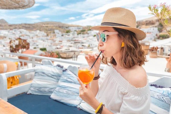 Glückliche asiatische Frau genießt Aperol Spritz Cocktail in einem griechischen Café. Getränke- und Erfrischungskonzept — Stockfoto