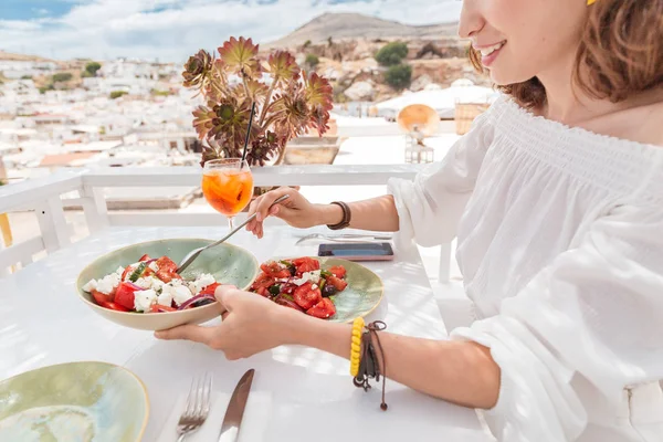 Frau isst leckeren griechischen Salat und trinkt Cocktail im Restaurant — Stockfoto