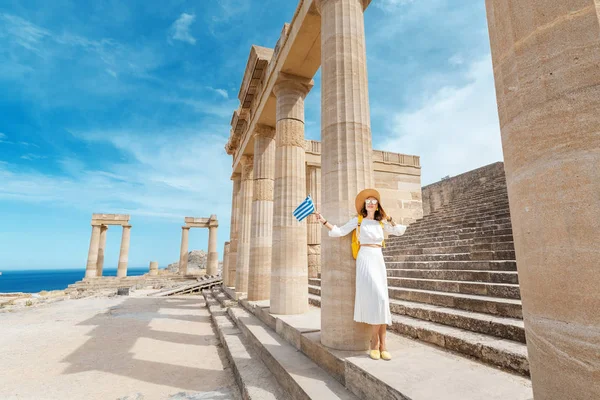 Antik Yunan harabelerinde Yunan bayrağı taşıyan genç bir gezgin kadın. Yunanistan 'da turizm kavramı