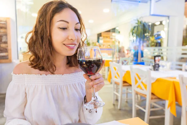 Молодая женщина пьет и дегустирует красное вино в ресторане — стоковое фото