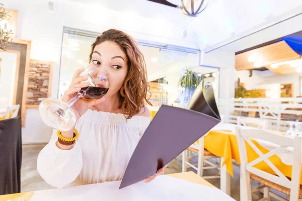 Mujer bebiendo vino y leyendo menú en el restaurante — Foto de Stock