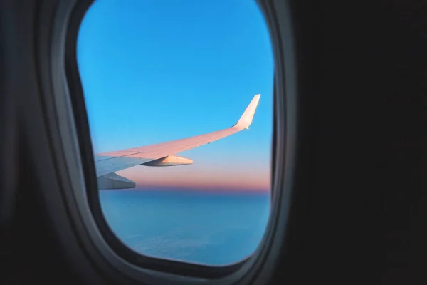 Vista desde la ventana del avión en el ala y los colores rosados de una majestuosa puesta de sol — Foto de Stock