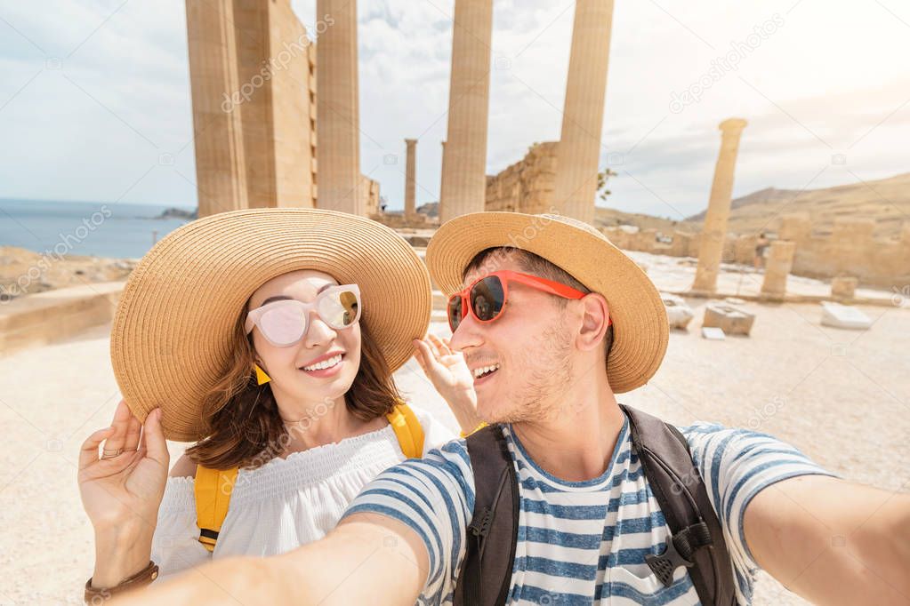 Young loving couple of tourists or friends travelers visiting ancient landmark Acropolis in Greece
