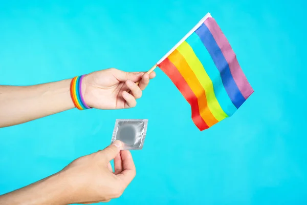 Main avec bracelet LGBT tenant un préservatif. Le concept de vie sexuelle sans risque pour les lesbiennes gays et les personnes transgenres — Photo