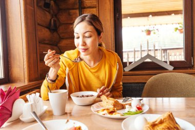 Ahşap evde rustik kahvaltı yiyen genç Asyalı kadın