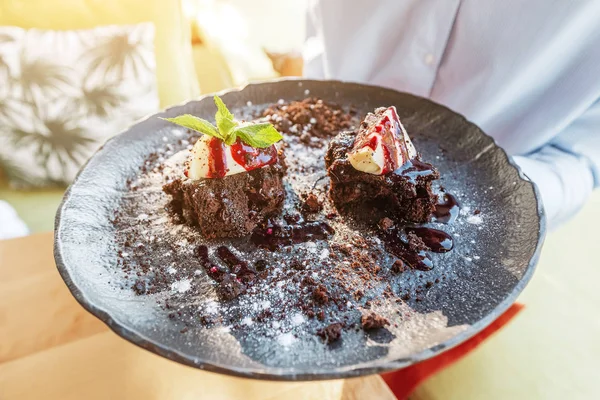 Das Mädchen schnuppert einen leckeren Kuchen auf einem Teller im Restaurant. das Konzept der süßen und kalorienreichen Nahrung — Stockfoto