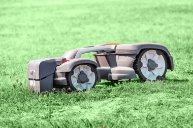 Robot otomatik çim biçme makinesi bir çim üzerinde çalışıyor. Yeni teknolojiler kavramı