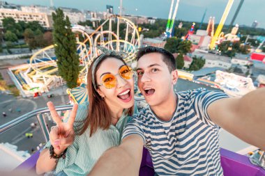 Loving karışık ırk çift sarılma ve dönme dolapta sürme ve eğlence Parkı'nda hafta sonu boyunca bir selfie fotoğrafı çekmek. Tarih ve ilişki