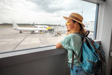 Havaalanında uçağa binmek için bekleyen sırt çantası ile gezgin kadın. Hava taşımacılığı konsepti