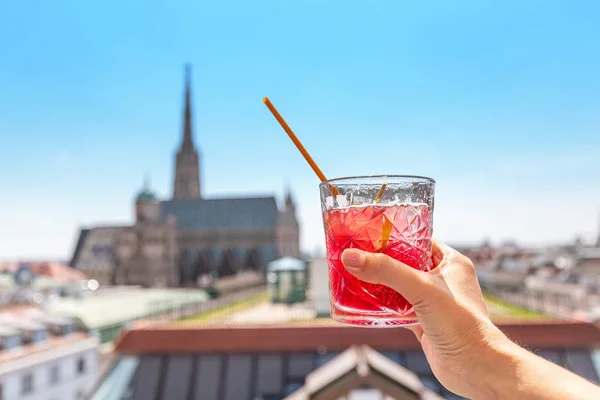 Hand mit einem Glas Cocktail mit Blick auf die Wiener Stadtlandschaft im Hintergrund — Stockfoto