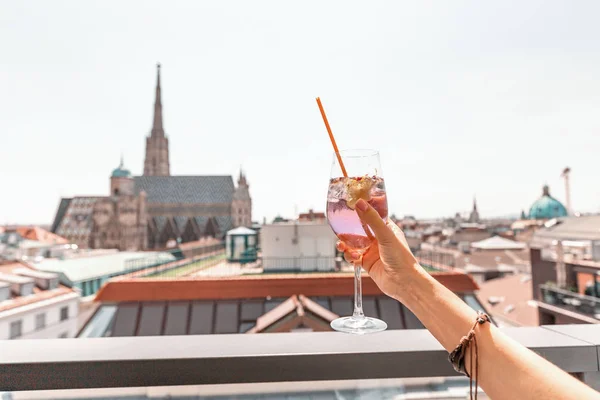 Χέρι με ποτήρι κοκτέιλ με θέα στο αστικό τοπίο της Βιέννης στο παρασκήνιο — Φωτογραφία Αρχείου