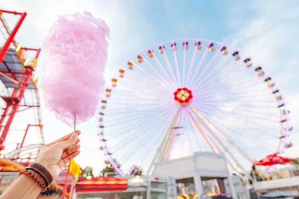 Donna felice mangiare gustoso zucchero filato rosa colorato di fronte alla grande ruota panoramica bianca al parco divertimenti in Europa — Foto Stock