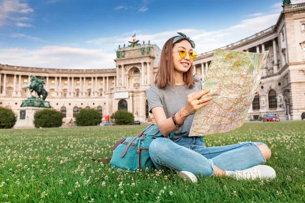 Joyeux voyageur asiatique avec carte assis sur une pelouse verte dans la ville de Vienne. Tourisme et vacances en Europe concept — Photo