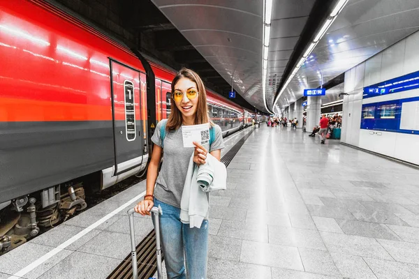 Дівчина мандрівник з багажем і валіза, що тримає квиток на поїзд або метро з qr-кодом — стокове фото