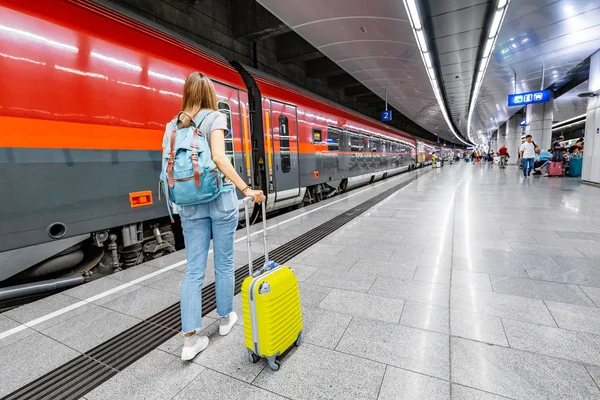 Cestujícímu žena s kufříkem pěšky do vlaku na nástupiště stanice metra na letišti — Stock fotografie