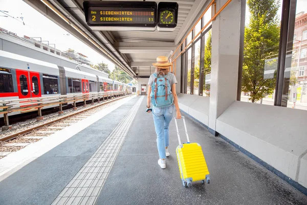 Žena s kufříkem u železničního nádraží. Koncepce letních prázdnin a dopravy — Stock fotografie