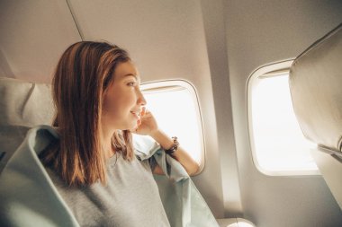Genç Asyalı kadın hava uçağı, seyahat ve ulaşım kavramı pencereye bakıyor