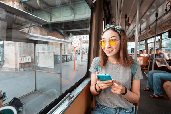 Tramvayda akıllı telefonu olan genç bir kadın. Ulaşım ve seyahat konsepti — Stok fotoğraf