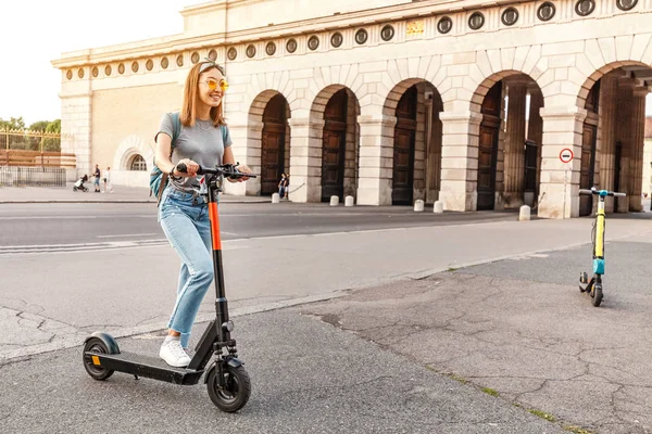 Mujer usando smartphone y alquilando scooter eléctrico moderno con una aplicación. Concepto de transporte urbano —  Fotos de Stock