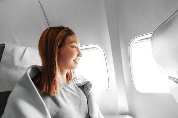 Genç Asyalı kadın hava uçağı, seyahat ve ulaşım kavramı pencereye bakıyor — Stok fotoğraf