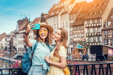 İki güzel Asyalı ve beyaz kız Strazburg, Alsace eyaletinin eski şehir önünde selfie çekerken