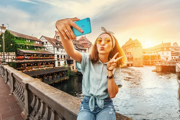 Щасливий і веселий Азіатські дівчата мандрівник приймає селфі на мосту Сен-Мартен в районі Петі Франс в Страсбурзі. Барвистий і драматичний захід сонця на задньому плані — стокове фото
