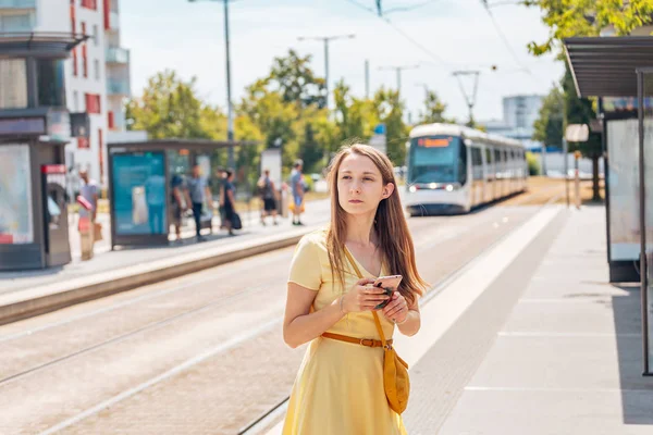 Gecikmiş bir tramvay için bekleyen bir akıllı telefon ile sinirli bir kız. — Stok fotoğraf