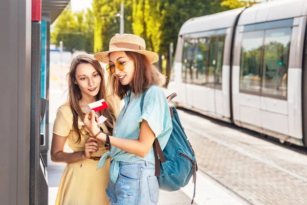 Дві дівчини друзі купують денний квиток на громадський транспорт у місті — стокове фото