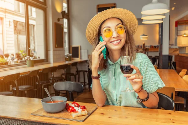 Женщина с помощью смартфона во время еды и питья красного итальянского вина — стоковое фото