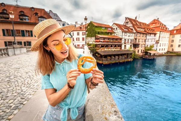 Ευτυχισμένο κορίτσι της Ασίας τουρίστρια τρώγοντας νόστιμο κουλούρι ενώ ταξιδεύουν στην Ευρώπη. Τουριστική και διατροφική έννοια — Φωτογραφία Αρχείου