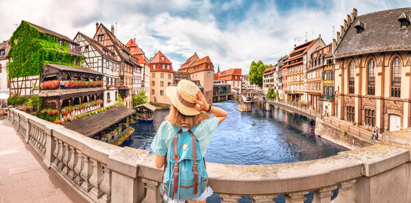 Young girl with backpack standing on a bridge over d Ill river in Strasbourg, France
