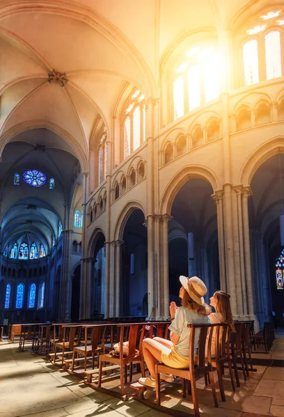 Dos chicas fieles rezando en una iglesia. La llamarada del sol prospera la ventana como símbolo de la respuesta de Dios y el perdón —  Fotos de Stock