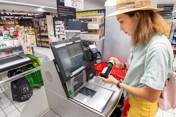 23 július 2019, Auchan szupermarket, Lyon, Franciaország: lány ügyfél vizsgál termékek az önkiszolgáló pénztár az élelmiszerboltban üzlet — Stock Fotó