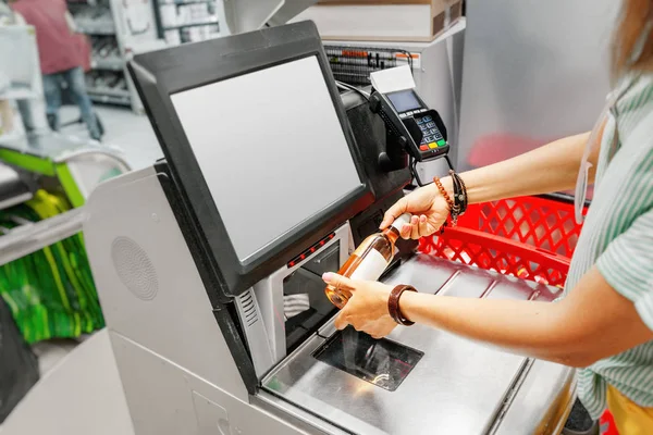 Kız müşteri bakkal süpermarket dükkanında self-servis checkout de şarap şişesi tarar