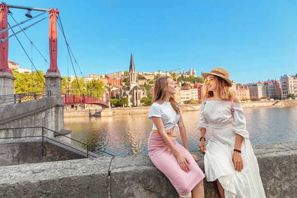 Dos amigas felices caminando por el puente peatonal de Saint Georges mientras viajan por el casco antiguo de Lyon en Francia — Foto de Stock