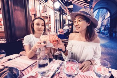 Akşam saatlerinde kafede bir kutlama an tadını çıkarırken iki karışık ırk kız arkadaşlar gözlük clinking