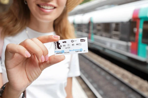 26 Julho 2019, Paris, França: Retrato de uma menina asiática segurando um pequeno bilhete inteligente eletrônico e esperando por um trem em uma plataforma ferroviária . — Fotografia de Stock
