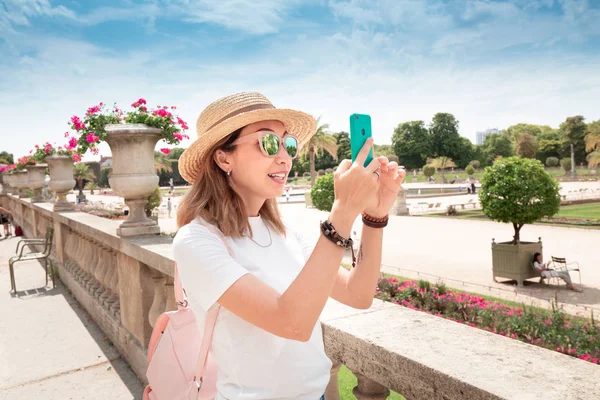 Jonge Aziatische uitziende blogger het nemen van Foto's op de smartphone voor sociale netwerken van het stedelijk landschap in de barokke tuin in Europa. Millennial reis-en lifestyle concept — Stockfoto