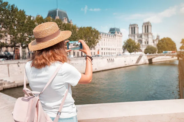 Happy traveler girl blogger tira fotos de Notre Dame De Paris e do rio Sena para suas mídias sociais — Fotografia de Stock