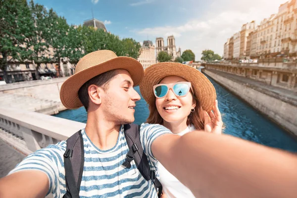 Par vänner tar Selfie foto från en bro över Seine River med Notre Dame Cathedral på bakgrunden — Stockfoto