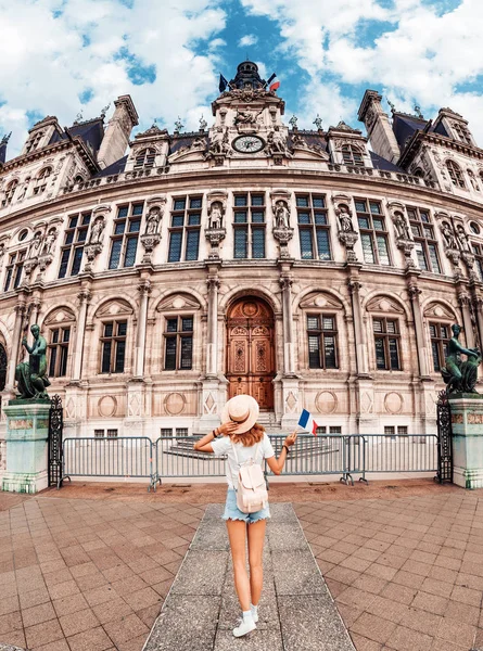 Привлекательная девушка-путешественница с симпатичным рюкзаком наслаждается видом на потрясающую готическую архитектуру старой ратуши в Париже. Ваши каникулы и приключения в Париже — стоковое фото