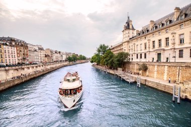 26 Temmuz 2019, Paris, Fransa: Paris'te Seine nehri üzerinde köprü ve yolcu gemisi olan bir hapishane olarak kullanılan ünlü konciergerie binası ile şehir silueti