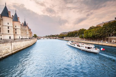 26 Temmuz 2019, Paris, Fransa: Paris'te Seine nehri üzerinde köprü ve yolcu gemisi olan bir hapishane olarak kullanılan ünlü konciergerie binası ile şehir silueti