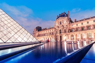 Işıklı dünyaca ünlü Louvre Müzesi kompleksi ve göletortasında inanılmaz şeffaf piramit ile Gece şehir manzarası. Paris ve Fransa'daki seyahat noktaları ve turistik yerler