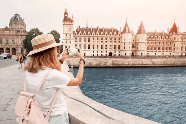 Podróżnik młoda dziewczyna spaceru w Paryżu i robienia zdjęć z jej smartphone z Conciergerie twierdzy i Sekwany — Zdjęcie stockowe