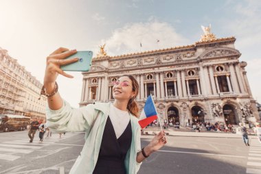 Paris Müzik Akademisi tarihi binasında Opera Garnier ana Cephe yakınında telefon ile mutlu Asyalı kız gezgin. Fransa'nın turistik yerleri ve kültürel cazibe merkezleri kavramı