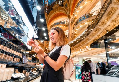 27 Temmuz 2019, Paris, Fransa: Asyalı kız Paris'teki Galerie Lafayette alışveriş merkezinde kozmetik seçerek