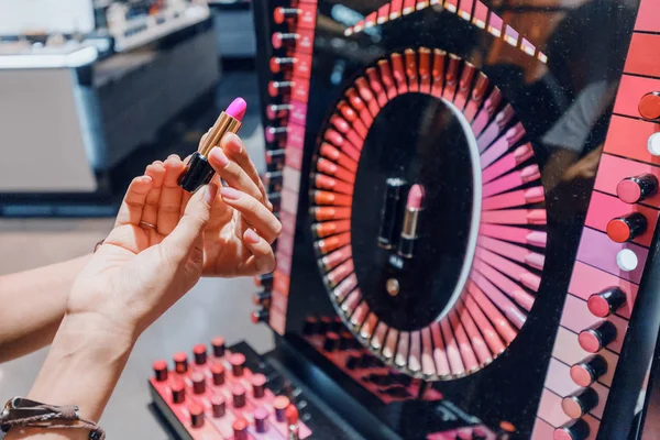 Девушка выбирает розовую блестящую помаду в женском магазине косметики — стоковое фото