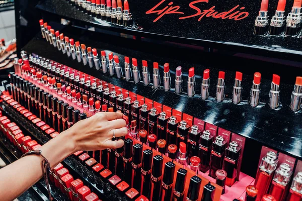 27 июля 2019, Париж, Франция: девушка выбирает розовую блестящую помаду в магазине женской косметики — стоковое фото