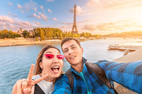 Ett lyckligt par i kärlek en man och en kvinna omfamna och ta en selfie på stranden av floden Seine med Eiffeltornet i bakgrunden. Resor och semester i Paris och Frankrike — Stockfoto